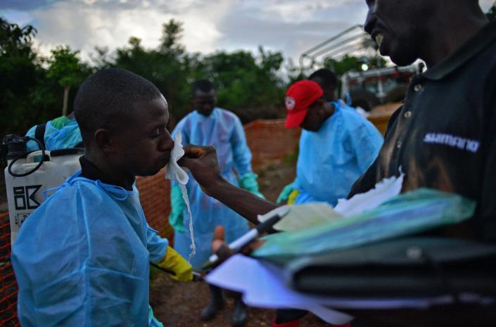 Sierra Leonese government burial team members are disinfected after loading the bodies of Ebola victims onto a truck in Kailahun, on August 14, 2014 (AFP Photo/Carl de Souza)