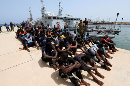 FILE PHOTO: Migrants sit at a naval base after being rescued by Libyan coastguards in Tripoli, Libya July 3, 2018. REUTERS/Ismail Zitouny/File Photo