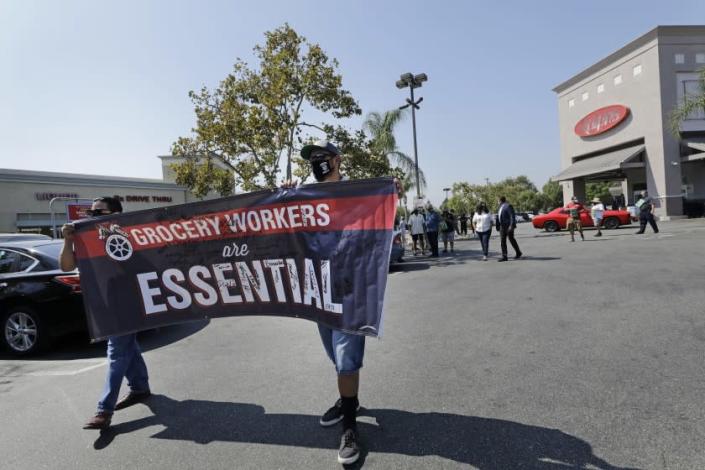 BURBANK, CA - SEPTEMBER 24: Grocery Teamsters Rene Ayala, left, and Jerry Soltero carry a banner during a Teamsters&#39; rally on Thursday, Sept. 24, 2020 in Burbank, CA to call for the protection of grocery workers health package through ongoing contract negotiations with their employers. (Myung J. Chun / Los Angeles Times)