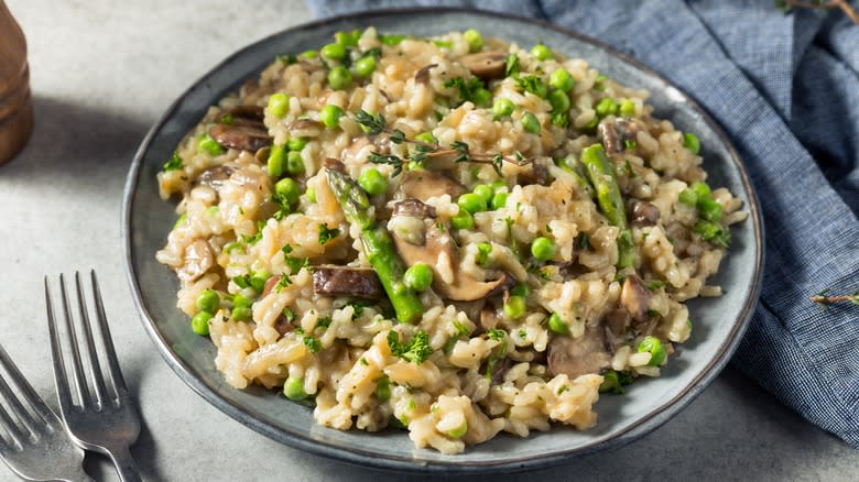 Bowl of asparagus and pea risotto next to blue linen