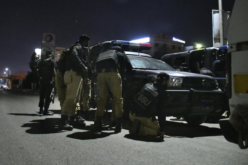 Police officers take position behind their vehicle close to the incident site following gunmen attack on police headquarters, in Karachi, Pakistan, Friday, Feb. 17, 2023. Militants launched a brazen attack on the police headquarters of Pakistan's largest city on Friday, officials said, as the sound of gunfire and grenade explosions rocked the heart of Karachi. (AP Photo/Ikram Suri)