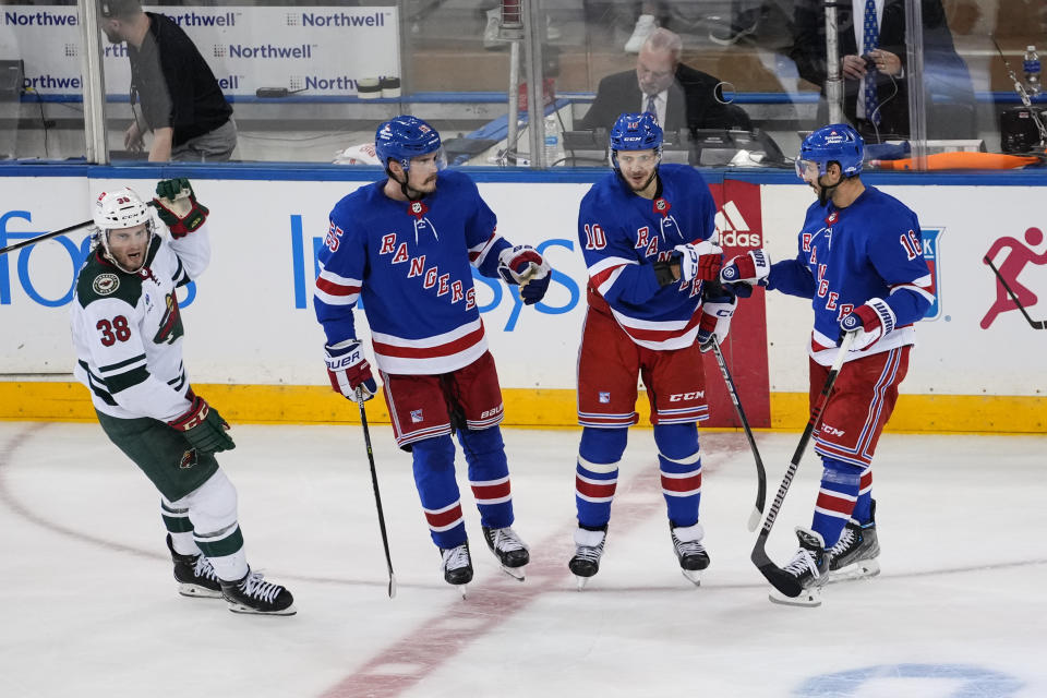 Minnesota Wild's Ryan Hartman (38) skates past New York Rangers' Artemi Panarin (10) as Panarin celebrates an empty-net goal with Ryan Lindgren (55) and Vincent Trocheck (16) during the third period of an NHL hockey game Thursday, Nov. 9, 2023, in New York. (AP Photo/Frank Franklin II)