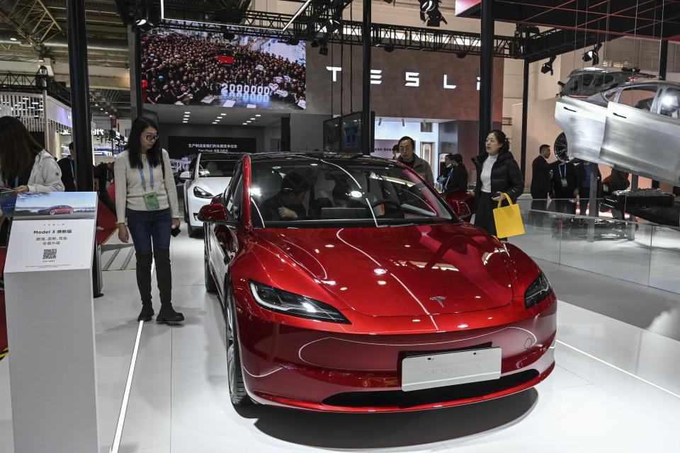 People try Tesla's electric vehicle Model 3 at its booth during the China International Supply Chain Expo.