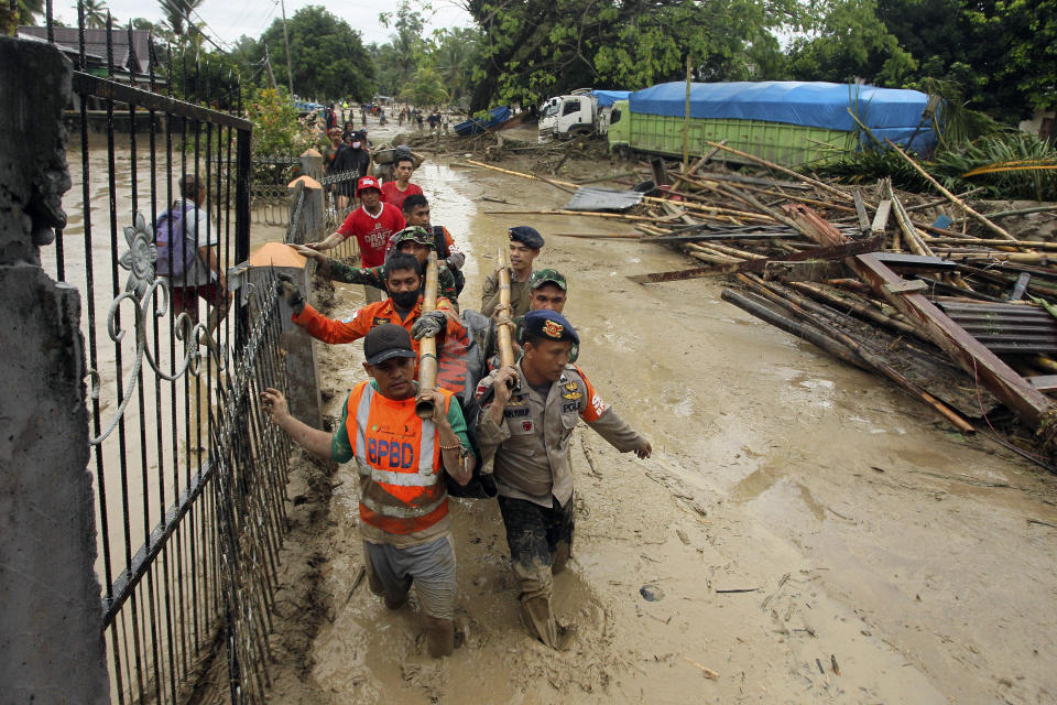 Rescuers wade through mud as they carry the body of a victim at an area affected by flash flood in Baebunta, South Sulawesi province, Indonesia, Tuesday, July 14, 2020. The flash flood left a number of people dead and missing, an official said Tuesday. (AP Photo)