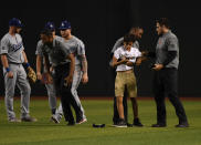 A young fan who ran onto the field checks his cell phone while being detained by security personnel after a game between the Arizona Diamondbacks and Los Angeles Dodgers at Chase Field on June 25, 2019 in Phoenix, Arizona. Dodgers won 3-2. (Photo by Norm Hall/Getty Images)