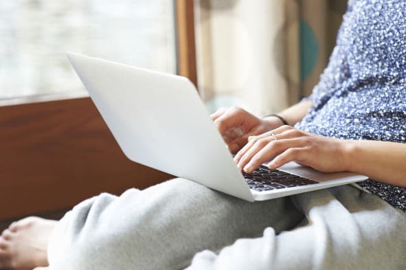 Woman using laptop at home, close up.