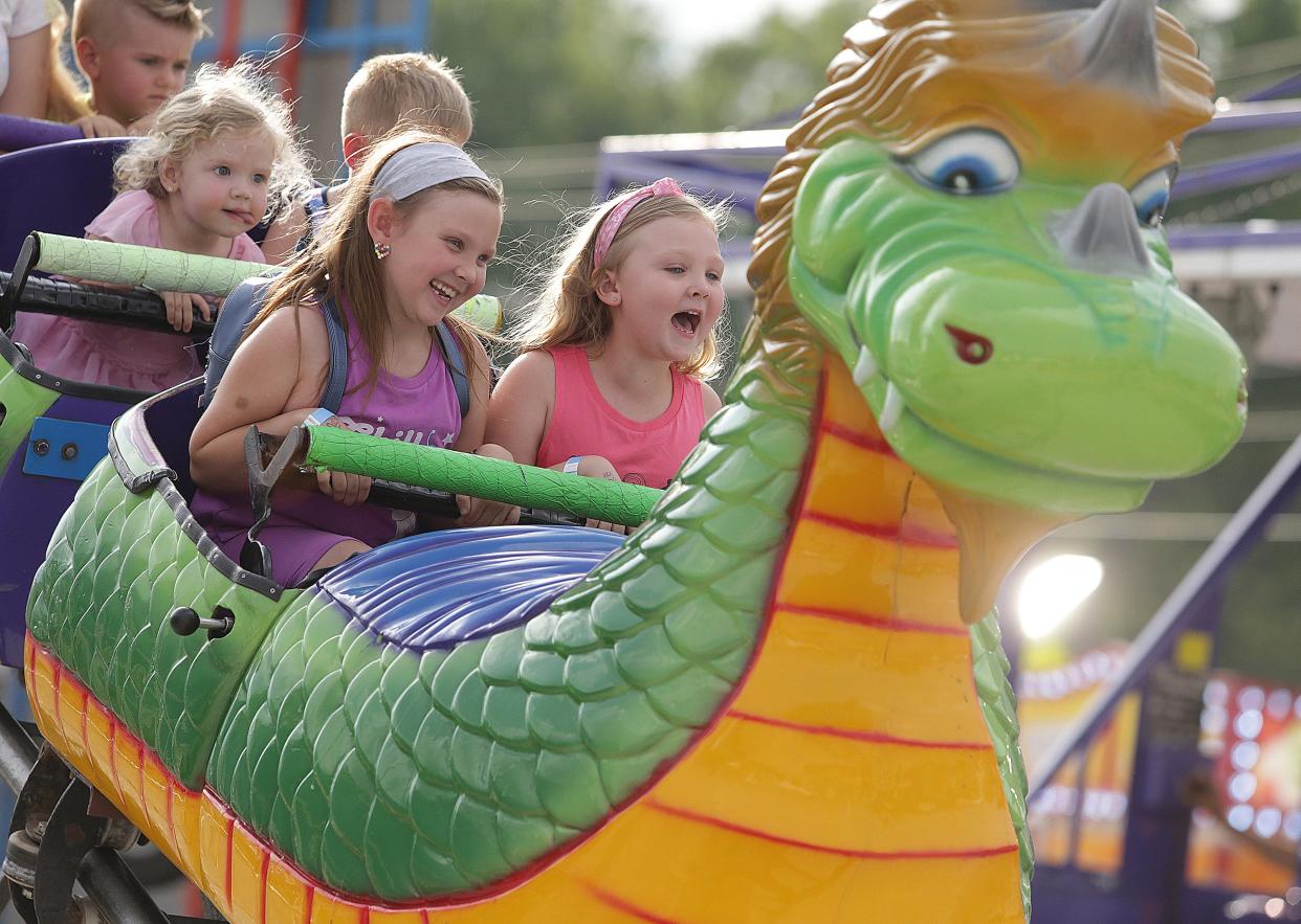 Cali Hartshorne, 7, left, and Avarie Hartshorne, 5, both of North Canton, ride the Dragon Wagon at the North Canton Jaycees Fair on Monday.