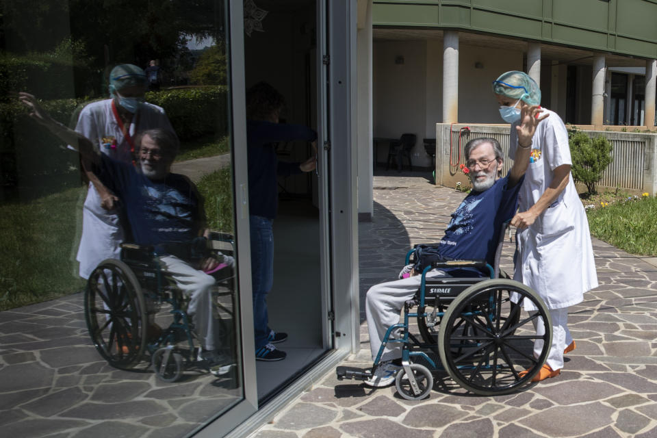 Elio Gabbiadini sits in a wheelchair pushed by Maria Giulia Badaschi, director, at the Martino Zanchi Foundation nursing home in Alzano Lombardo, Italy, Friday, May 29, 2020. Loved ones are being allowed to reunite with residents of the Martino Zanchi Foundation nursing home in the northern Italian town of Alzano. It comes after more than three months of separation and worry amid the coronavirus pandemic. (AP Photo/Luca Bruno)