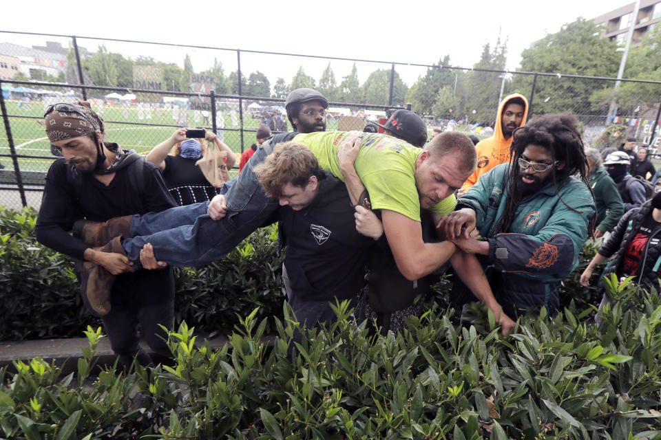 A group of people try to carry a street preacher away from Cal Anderson Park, Saturday, June 20, 2020, in the Capitol Hill Occupied Protest zone in Seattle. The man and another person working with him clashed with protesters and others throughout the day as they yelled homophobic slurs, played loud music, and shouted sermons. The conflict was in addition to tensions from a pre-dawn shooting near the area that left one person dead and critically injured another person. The area has been occupied by protesters after Seattle Police pulled back from several blocks of the city's Capitol Hill neighborhood near the Police Department's East Precinct building. (AP Photo/Ted S. Warren)