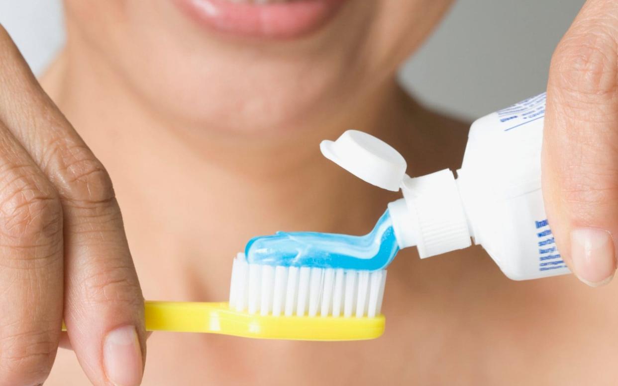 A woman putting toothpaste on toothbrush - Digital Vision