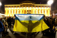 A demonstrator holds a Ukrainian national flag in front of the Georgian Parliament during an action against Russia's attack on Ukraine in Tbilisi, Georgia, Tuesday, March 1, 2022. Russian shelling pounded civilian targets in Ukraine's second-largest city again, and a 40-mile convoy of tanks and other vehicles threatened the capital. (AP Photo/Shakh Aivazov)