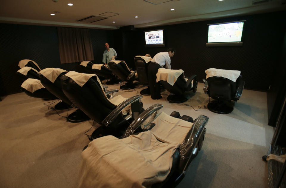 In this Monday, Oct. 29, 2012 photo, manager Akiyoshi Kaneko, right, checks a chair at the Capsule & Sauna Century Shibuya in Tokyo. The capsule concept has been around for at least 30 years, starting out as lodging for businessmen working or partying late who missed the last train home and needed a cheap place to crash. But budget travelers and other folks curious about a unique lodging experience use them too. (AP Photo/Shizuo Kambayashi)