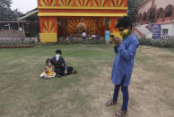 A boy checks his mobile phone as his sister and brother sit by a deserted worship venue for Durga Puja festival in New Delhi, India, Thursday, Oct. 22, 2020. The Hindu festival of Durga Puja, a time for devotional dancing in front of the idols of Goddess Durga, the eight-arms deity worshipped for her graciousness as well as her fearsome power, is bereft of all the grandiose that accompanies the rituals because of the coronavirus pandemic. There are no majestic idols, fairs, or cultural performances either. (AP Photo/Manish Swarup)