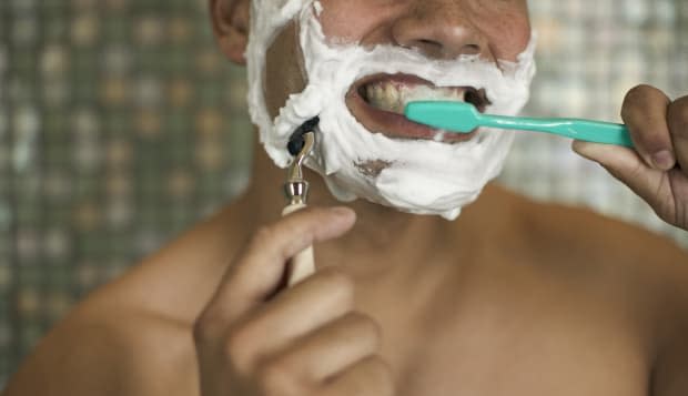Man Shaving while Brushing His Teeth