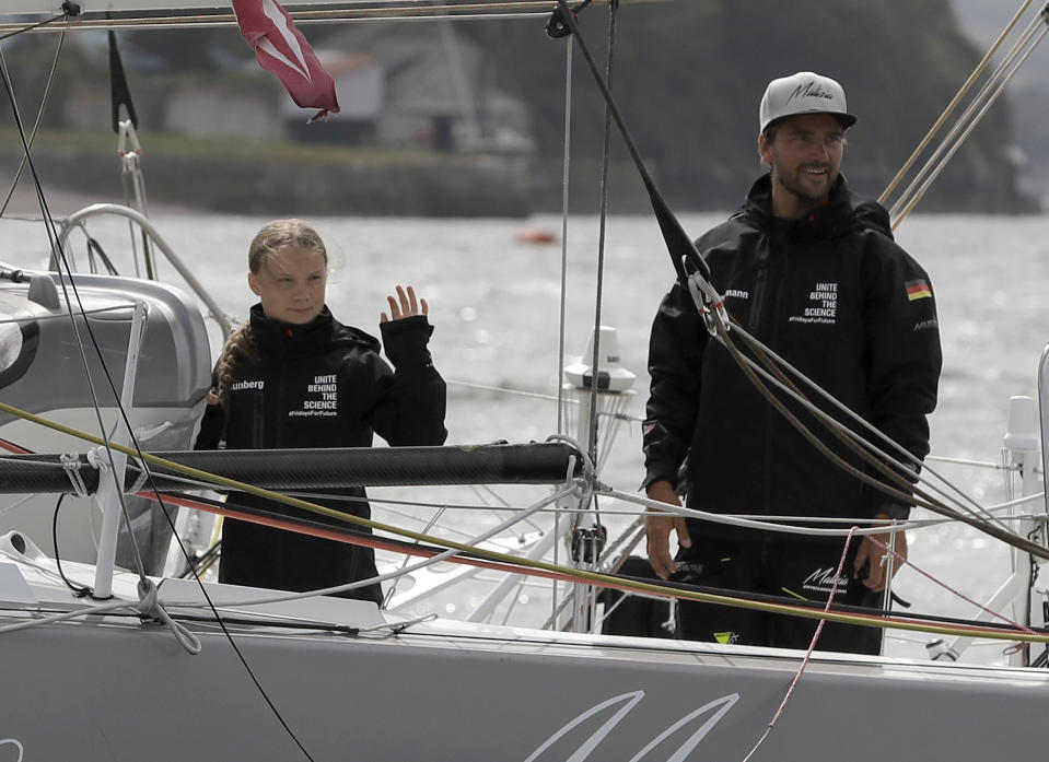 Climate change activist Greta Thunberg and skipper Boris Herrmann wave from the Malizia II boat in Plymouth, England, Wednesday, Aug. 14, 2019. The 16-year-old climate change activist who has inspired student protests around the world will leave Plymouth, England, bound for New York in a high-tech but low-comfort sailboat.(AP Photo/Kirsty Wigglesworth, pool)