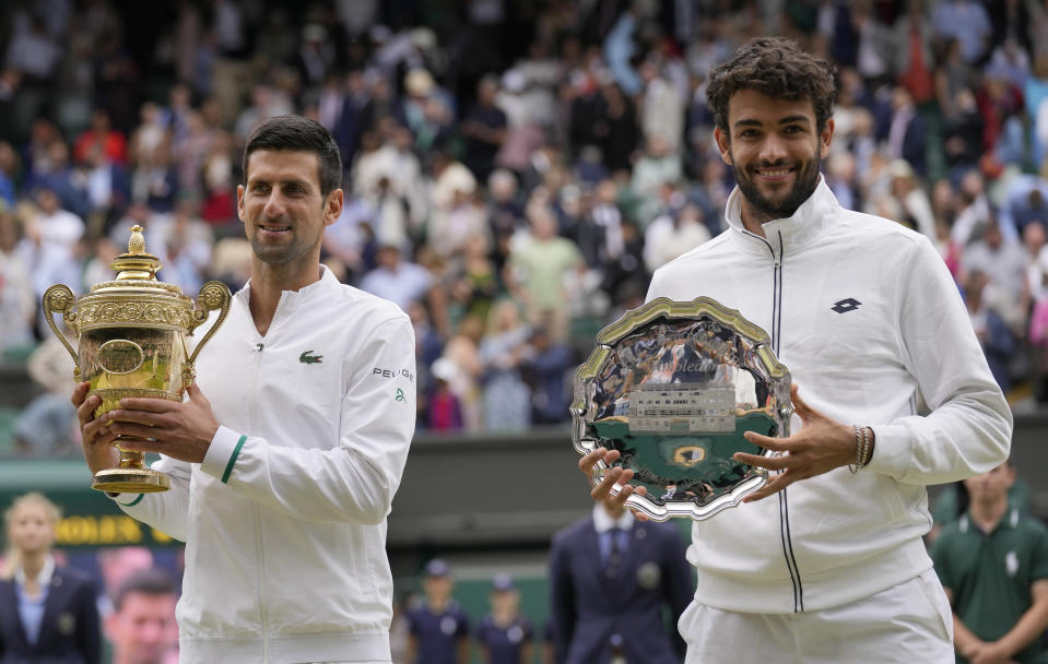 Serbia's Novak Djokovic, left holds the winners trophy after he defeated Italy's Matteo Berrettini who holds his runners-up plate as they pose for a photograph following the men's singles final on day thirteen of the Wimbledon Tennis Championships in London, Sunday, July 11, 2021. (AP Photo/Kirsty Wigglesworth)