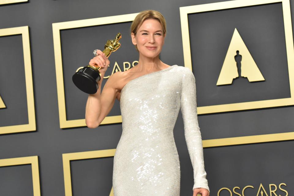 Renée Zellweger holding her Oscar for "Judy" in a white, one-shoulder dress