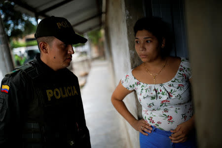 A Venezuelan woman looks at a Colombian police officer entering a house where undocumented Venezuelans migrants live during a raid in Villa del Rosario, Colombia August 24, 2018. REUTERS/Carlos Garcia Rawlins