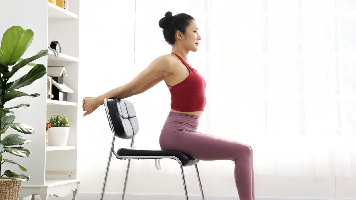  A photo of a woman stretching in a chair. 