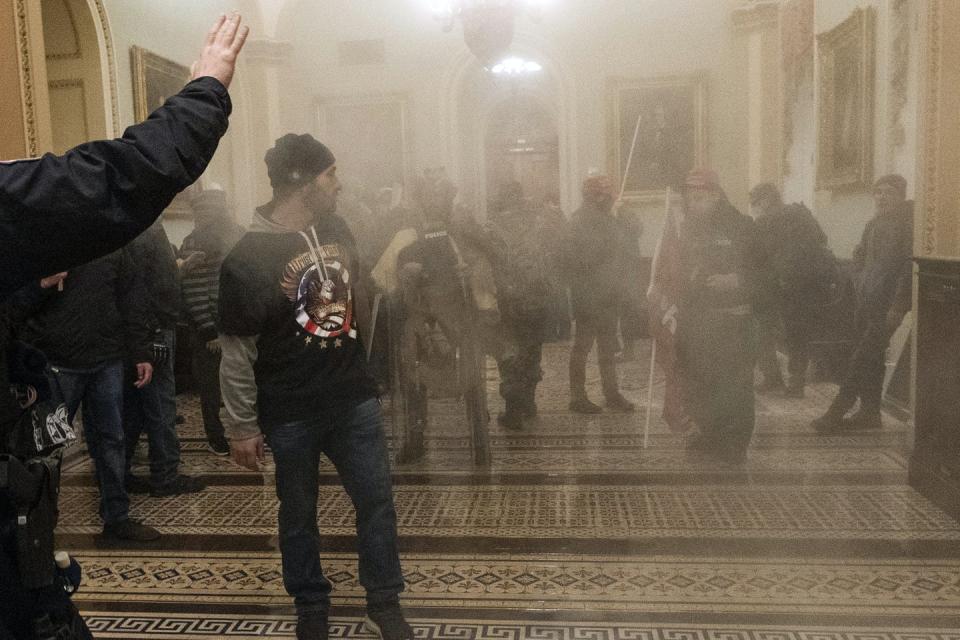 Smoke fills a hall inside the Capitol where Trump supporters are standing.