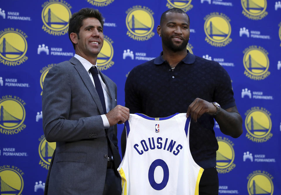 FILE - In this July 19, 2018, file photo, Golden State Warriors General Manager Bob Myers, left, holds a jersey with DeMarcus Cousins during a media conference in Oakland, Calif. Cousins can't wait to join what would be a starting lineup featuring five All-Stars. (AP Photo/Ben Margot, File)