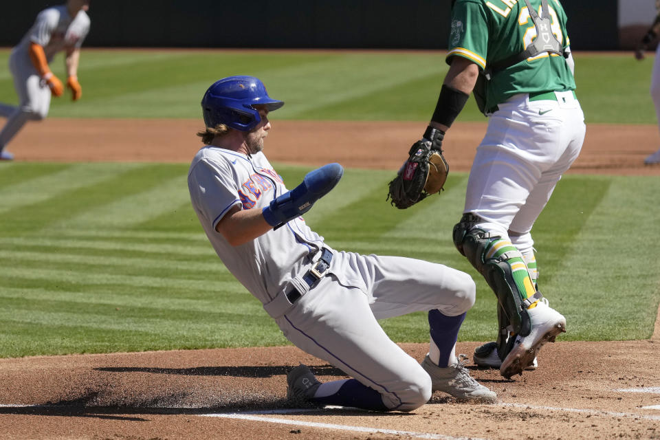 New York Mets' Jeff McNeil, left, slides into home plate to score a run on a sacrifice fly by Francisco Lindor against the Oakland Athletics during the first inning of a baseball game in Oakland, Calif., Saturday, Sept. 24, 2022. (AP Photo/Tony Avelar)