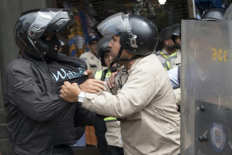 A Venezuelan pro-government supporter scuffles with riot police in Caracas, on March 31, 2017