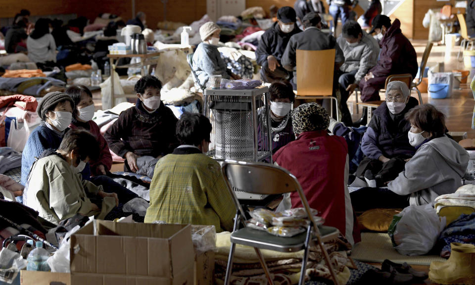 Evacuees warm up together in a shelter in the earthquake-hit Anamizu, Ishikawa prefecture, Monday, Jan. 8, 2024. Thousands of people made homeless overnight are living in weariness and uncertainty on the western coast of Japan a week after powerful earthquakes hit the region. (Kyodo News via AP)