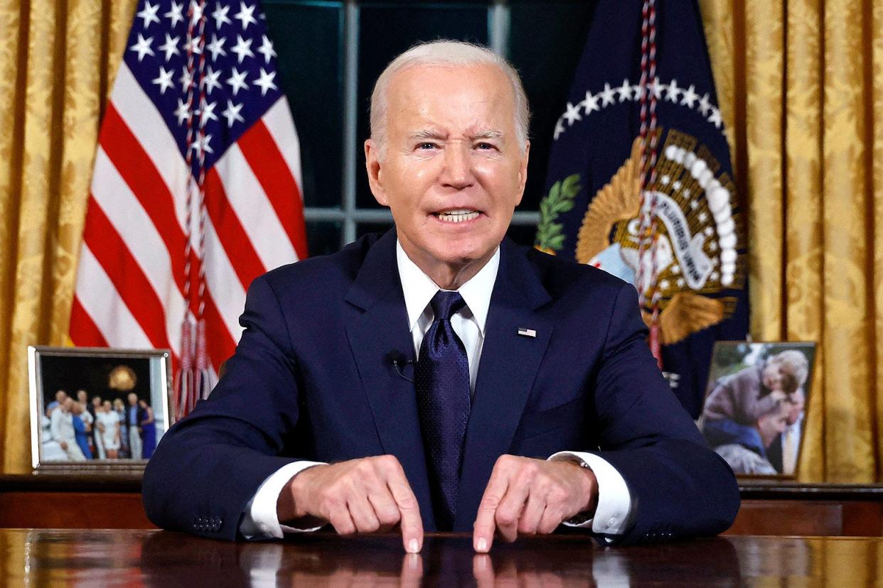 Joe Biden giving a speech from the White House, pointing at his desk with a determined expression on his face.