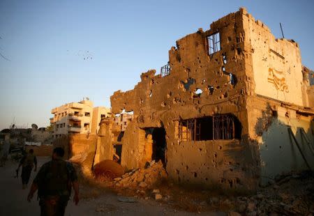 Fighters from the Free Syrian Army's Al Rahman legion walk past damaged buildings in the rebel held Jobar, a suburb of Damascus, Syria September 6, 2016. Picture taken September 6, 2016. REUTERS/Bassam Khabieh