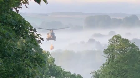 A RAF Chinook helicopter carries sacks of aggregate to drop it at the damaged dam site in Whaley Bridge