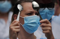 A nurse hits with spoons as medical staff demonstrate at the Robert Debre hospital in Paris, Thursday, June 4, 2020. French nurses and doctors demand better pay and a rethink of a once-renowned public health system that found itself quickly overwhelmed by tens of thousands of virus patients. (AP Photo/Francois Mori)