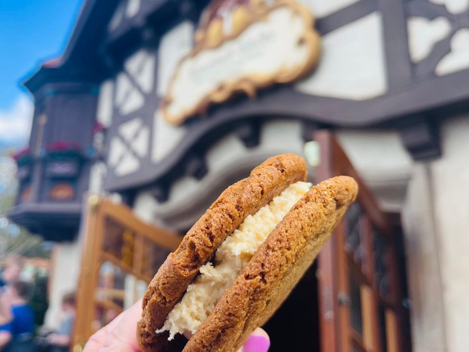hand holding cookie frosting sandwich in front of the bakery in germany at epcot