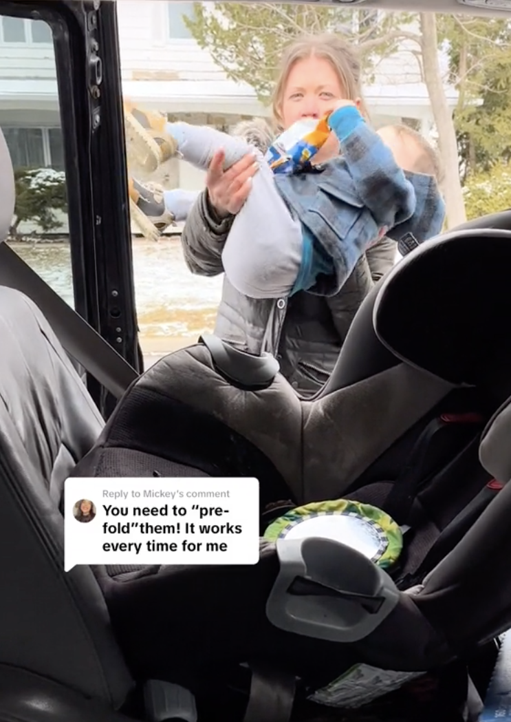 Woman demonstrates folding technique with baby clothes near a car seat; text bubble: "You need to 'pre-fold' them! It works every time for me"