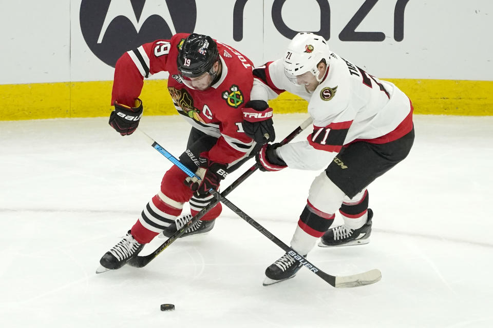 Chicago Blackhawks' Jonathan Toews (19) and Ottawa Senators' Chris Tierney vie for a loose puck during the second period of an NHL hockey game Monday, Nov. 1, 2021, in Chicago. (AP Photo/Charles Rex Arbogast)