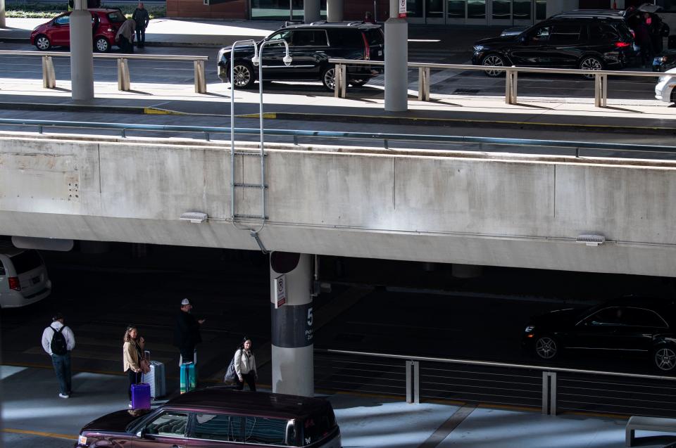 A family waits for their car to arrive at the arrival gate while cars a level above them are leaving for their flight at the BNA Airport in Nashville, Tenn., Wednesday, Nov. 29, 2023.