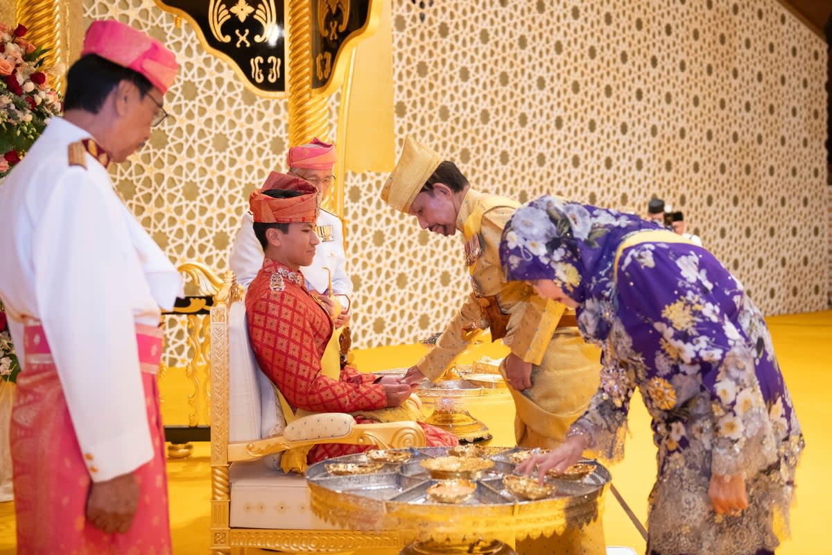 This picture taken by Brunei's Information Department on 10 January 2024 shows Brunei's Sultan Hassanal Bolkiah, centre right, greeting Brunei's Prince Abdul Mateen's, center, during the royal powdering ceremony at Istana Nurul Iman, ahead of his wedding to Anisha Rosnah, in Bandar Seri Begawan, Brunei (AP)