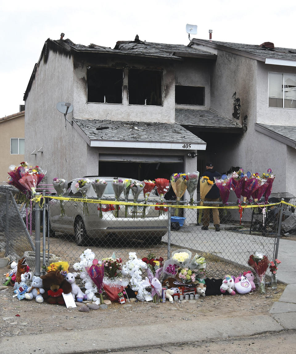 Flowers, stuffed animals and candles are placed on and along a chain-link fence in a makeshift memorial outside the Bullhead City, Ariz., duplex where five children were killed in a fire on Saturday, Dec. 16, 2023. Authorities have yet to determine what caused the house fire. (Bill McMillen/Mohave Valley Daily News via AP)