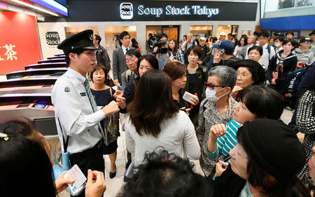 Passengers gather around a railway company staff as they try to gather information after train services were suspended because of a power outage, caused by a fire at an underground cable facility, at a station in Tokyo, Japan October 12, 2016. Kyodo/via REUTERS