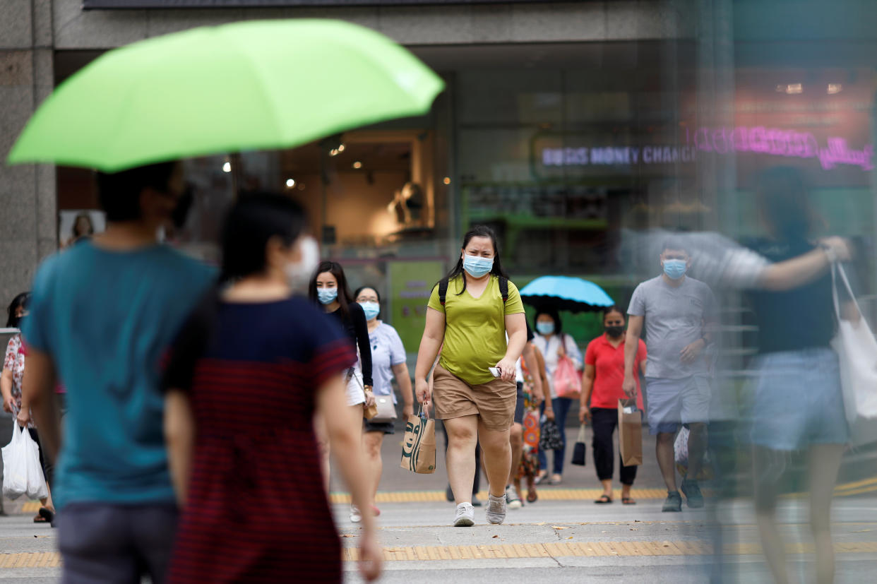 People wearing protective face masks cross a street, amid the coronavirus disease outbreak, in Singapore on 14 July, 2020. (PHOTO: Reuters)