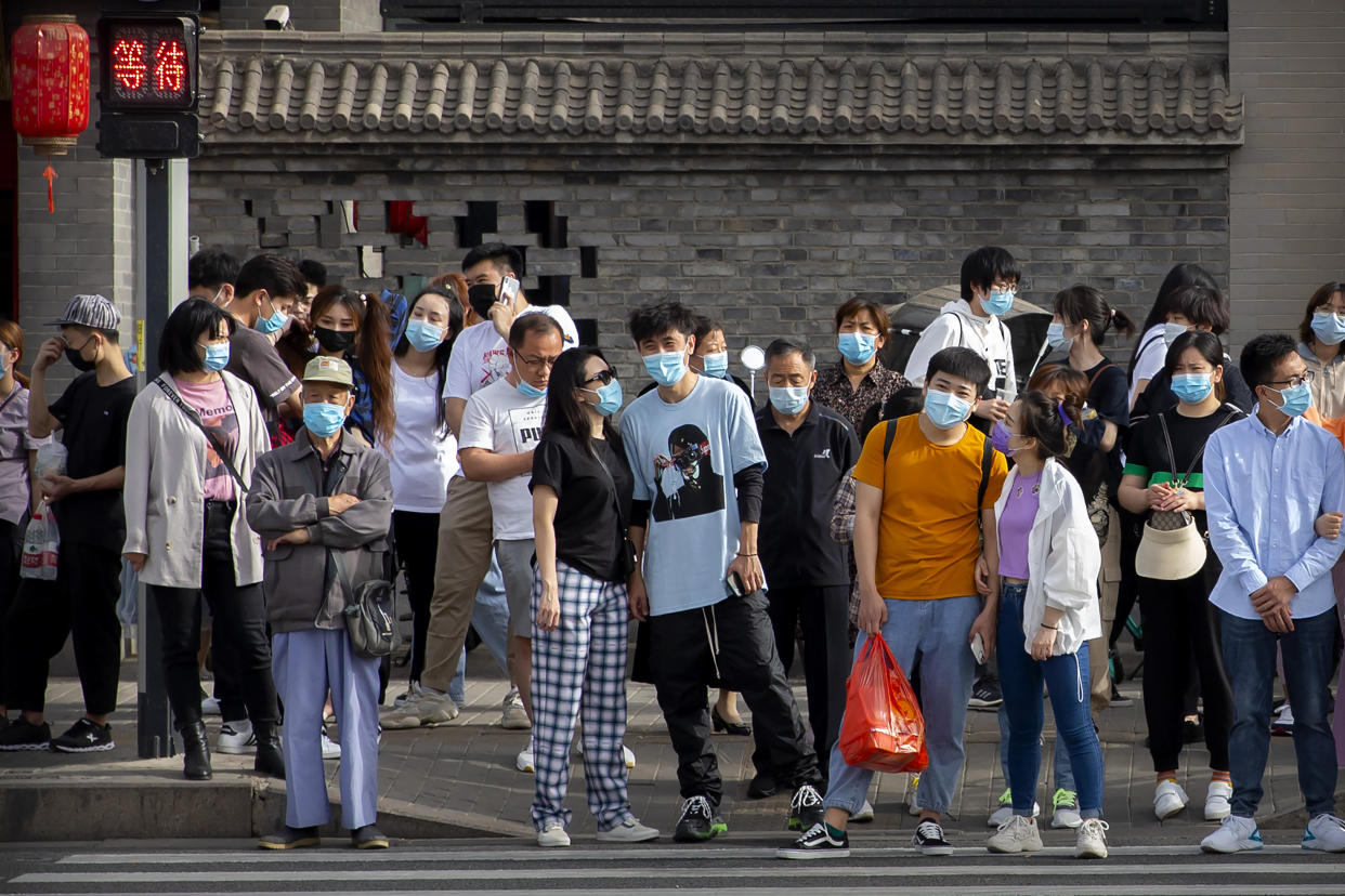 People wearing face masks to protect against the spread of the new coronavirus wait to cross an intersection in Beijing, Saturday, May 16, 2020. According to official data released on Saturday India's confirmed coronavirus cases have surpassed China's. (AP Photo/Mark Schiefelbein)