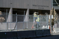Workers install barbed wire on fencing outside the Hennepin County Government Center, Wednesday, Feb. 23, 2021 in Minneapolis, as part of security preparation for the trial of former Minneapolis police officer Derek Chauvin. The trial is slated begin with jury selection on March 8. Chauvin is charged with murder the death of George Floyd during an arrest last May in Minneapolis. (AP Photo/Jim Mone)