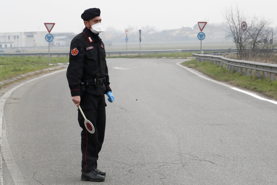 Carabinieri (Italian paramilitary police) officer checks enter or leave the cordoned area in Casalpusterlengo, Italy, Tuesday, Feb. 25, 2020. A dozen Italian towns saw daily life disrupted after the deaths of two people infected with the virus from China and a pair of case clusters without direct links to the outbreak abroad. A rapid spike in infections prompted authorities in the northern Lombardy and Veneto regions to close schools, businesses and restaurants and to cancel sporting events and Masses. (AP Photo/Antonio Calanni)