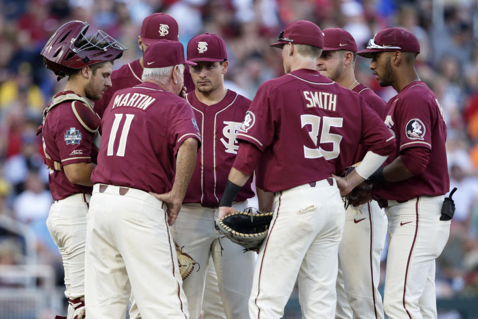 Florida State coach Mike Martin (11) talks to pitcher Drew Parrish, center, during a meeting on the mound in the seventh inning of an NCAA College World Series baseball game against Arkansas in Omaha, Neb., Saturday, June 15, 2019. (AP Photo/Nati Harnik)