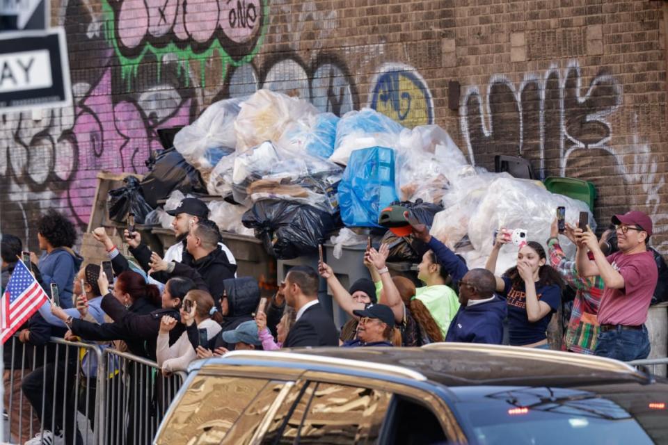 People cheer as a motorcade carrying Donald Trump drives through Harlem.