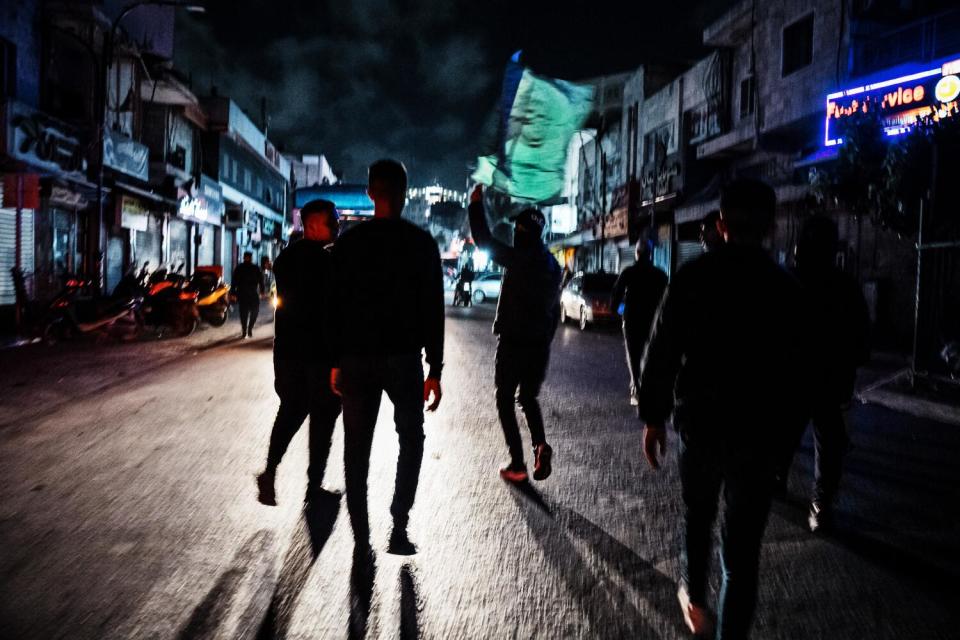 People stand on a street, one waving a green flag