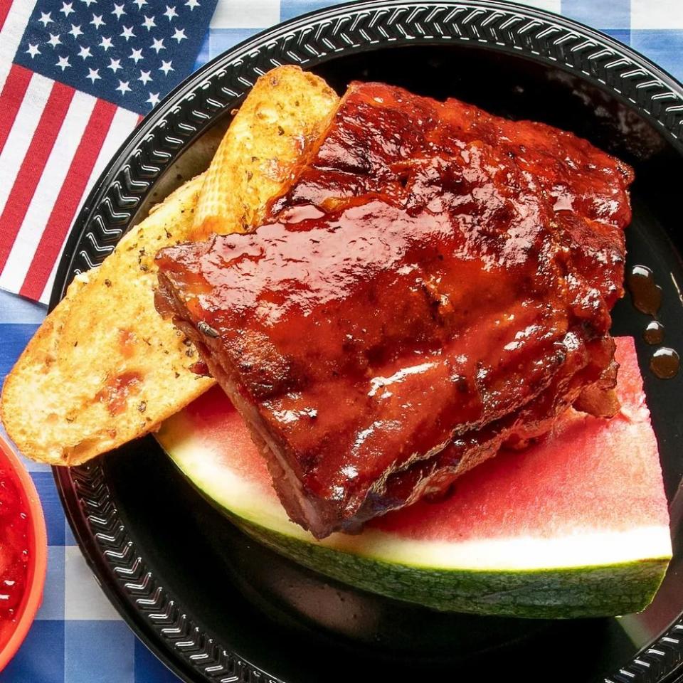 sweet and smoky ribs with watermelon and slice of bread on black plate