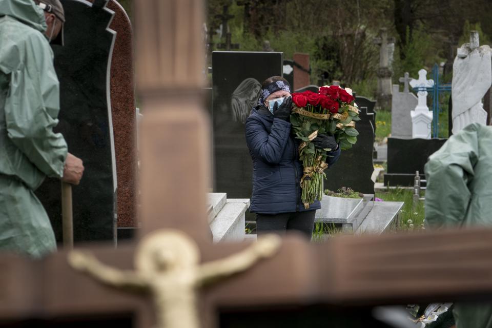 In this photo taken on Saturday, May 2, 2020, Nadiya Muchka cries during the burial of their father Semen Muchka, a 71-year-old who died from the COVID-19 virus in Krynytsya, Ukraine, Saturday. Ukraine's troubled health care system has been overwhelmed by COVID-19, even though it has reported a relatively low number of cases. (AP Photo/Evgeniy Maloletka)