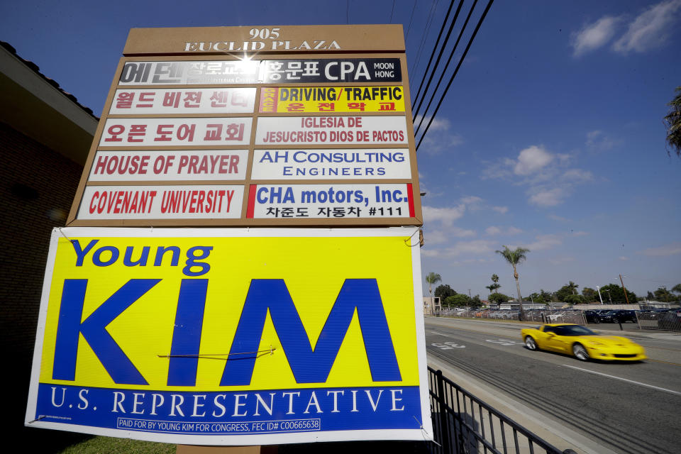 FILE - In this Wednesday, Oct. 10, 2018, file photo a campaign poster for Young Kim, a Republican running for a U.S. House seat in the 39th District in California, hangs on a building sign advertising in multiple languages in Fullerton, Calif. Kim lost to Democrat Gil Cisneros. Orange County's Registrar of Voters reports Wednesday, Aug. 7, 2019, there are 89 more Democrats than Republicans among its 1.6 million registered voters. (AP Photo/Chris Carlson, File)