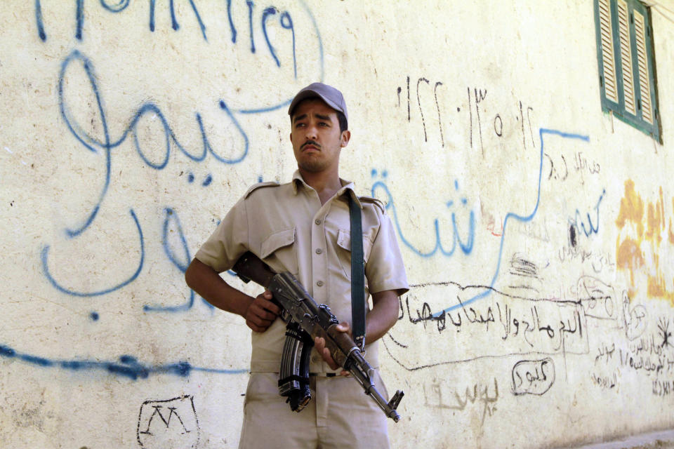 A policeman stands guard as Egyptian prosecutor general, Hisham Barakat, tours the area where fighting took place on Friday, April 4, between a Nubian family and members of the Arab Haleyla clan, in the southern city of Aswan, Egypt, Tuesday, April 8, 2014. Telephone and internet networks were briefly shut down to Egypt’s southern province of Aswan for several hours, as authorities moved to try to end a bloody tribal feud that killed tens the past week, security officials and residents said Tuesday. (AP Photo/Sabry Khaled, El Shorouk Newspaper) EGYPT OUT